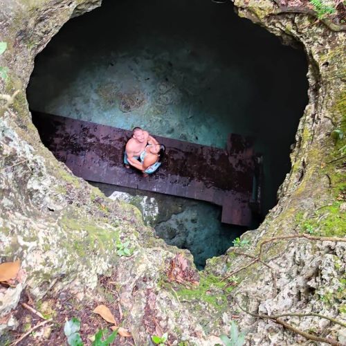 Overview of a couple hugging standing on the other side of a sinkhole looking up